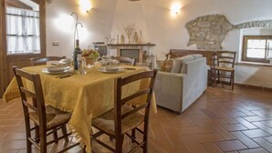 A rustic dining area with a wooden table set for two, a stone fireplace, and a cozy seating arrangement. - Agriturismo Antee by Interhome (Arcidosso)