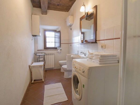 A small, clean bathroom with a toilet, sink, and washing machine.