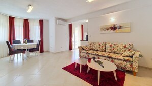 Ein modernes Wohnzimmer mit einer Couch, einem Esstisch, Stühlen und einem roten Teppich.