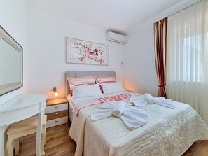 Une chambre d’hôtel équipée d’un lit, d’un bureau, d’une table de chevet, d’un appareil de climatisation et d’une fenêtre avec des rideaux.