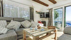 A living room with a sofa, a glass coffee table, and a television.