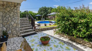 Un edificio in pietra con piscina, area salotto all'aperto e una scala che conduce a un patio.