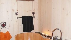 A wooden bathtub with a faucet, a towel rack with a towel, and a framed picture on the wall. - Chalet La Poya by Interhome (Moléson-sur-Gruyères)