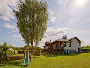 A two-story house with a covered porch, a swing set, and a slide in the yard. - Trzy Brzozy by Interhome (Parchowo-Karlowo)