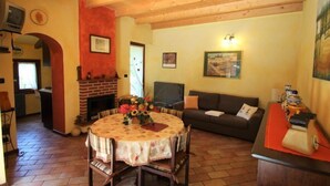 Una sala de estar acogedora con chimenea, una mesa redonda de comedor y un sofá.
