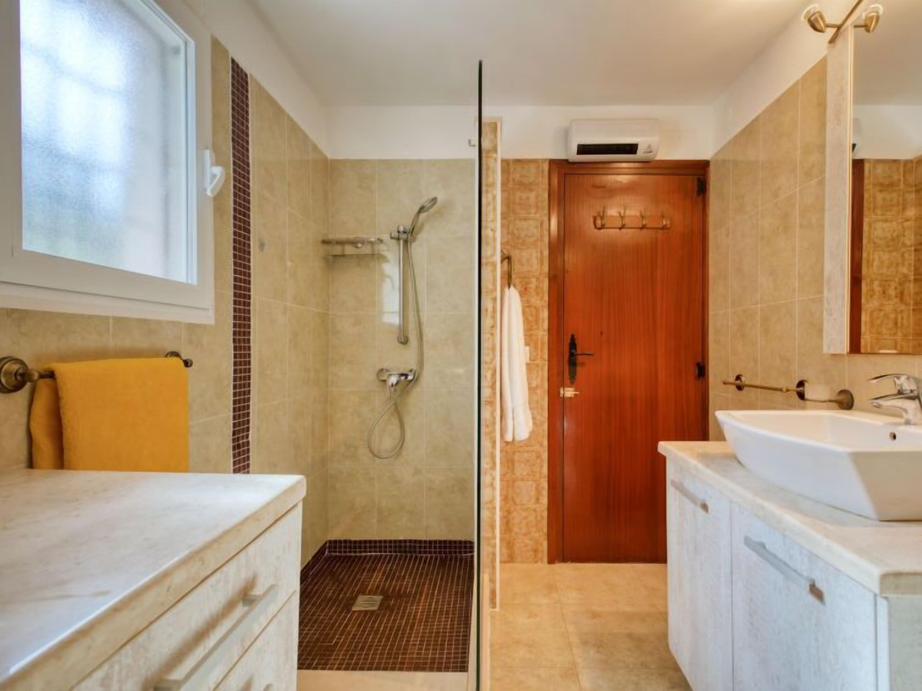 Une salle de bain moderne avec une douche, un lavabo et une porte en bois.