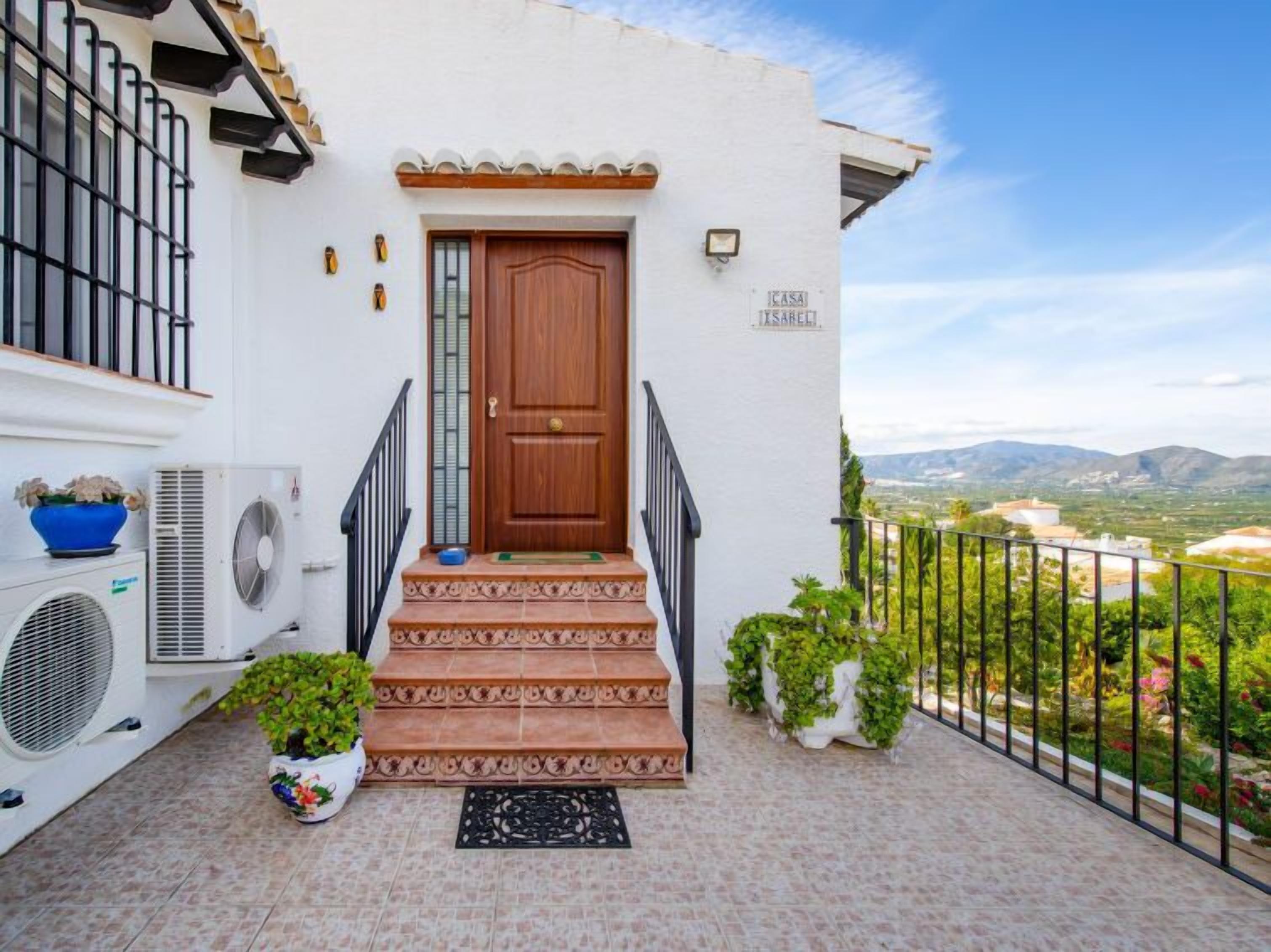 A white building with a wooden door, air conditioning units, and a view of the countryside.