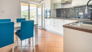 A modern kitchen with white cabinets, a black marble backsplash, and a large window overlooking a scenic view. - Miškulin by Interhome (Senj)