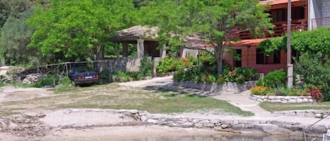 A house with a stone foundation, surrounded by lush greenery and a small pond.