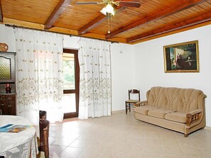 Cozy living space with a high ceiling, sofa, chair, and table.