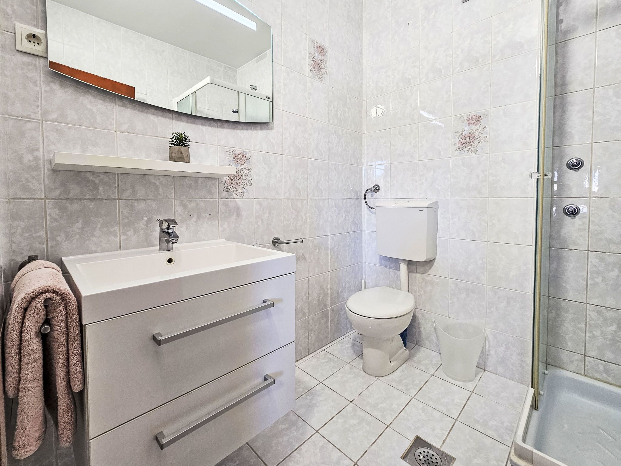 A modern bathroom with a white sink, a toilet, and a shower area.