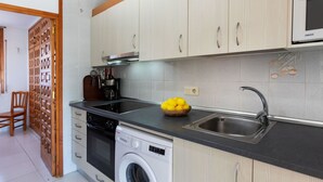 A modern kitchen with a built-in oven, microwave, and washing machine.