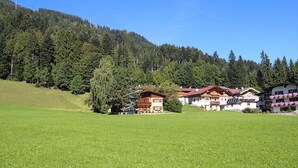A hotel with multiple buildings, a green field, and a forested hill in the background. - Vacation home Hussl by Interhome (Fügen)