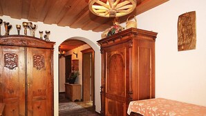 A wooden hallway with a rug, a bed with a floral bedspread, and a large wooden cabinet with a decorative top. - Vacation home Hussl by Interhome (Fügen)