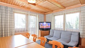 A cozy cabin-style room with a wooden ceiling, a television, a sofa, and a dining table with chairs. - Vacation home Hussl by Interhome (Fügen)