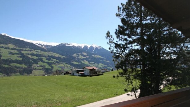 A view of a mountain landscape with a clear sky, a green field, and a building with a red roof. - Vacation home Hussl by Interhome (Fügen)