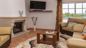 A living room with a fireplace, a television mounted on the wall, a sofa, and a coffee table. - Das Amendoeiras by Interhome (Alcantarilha)