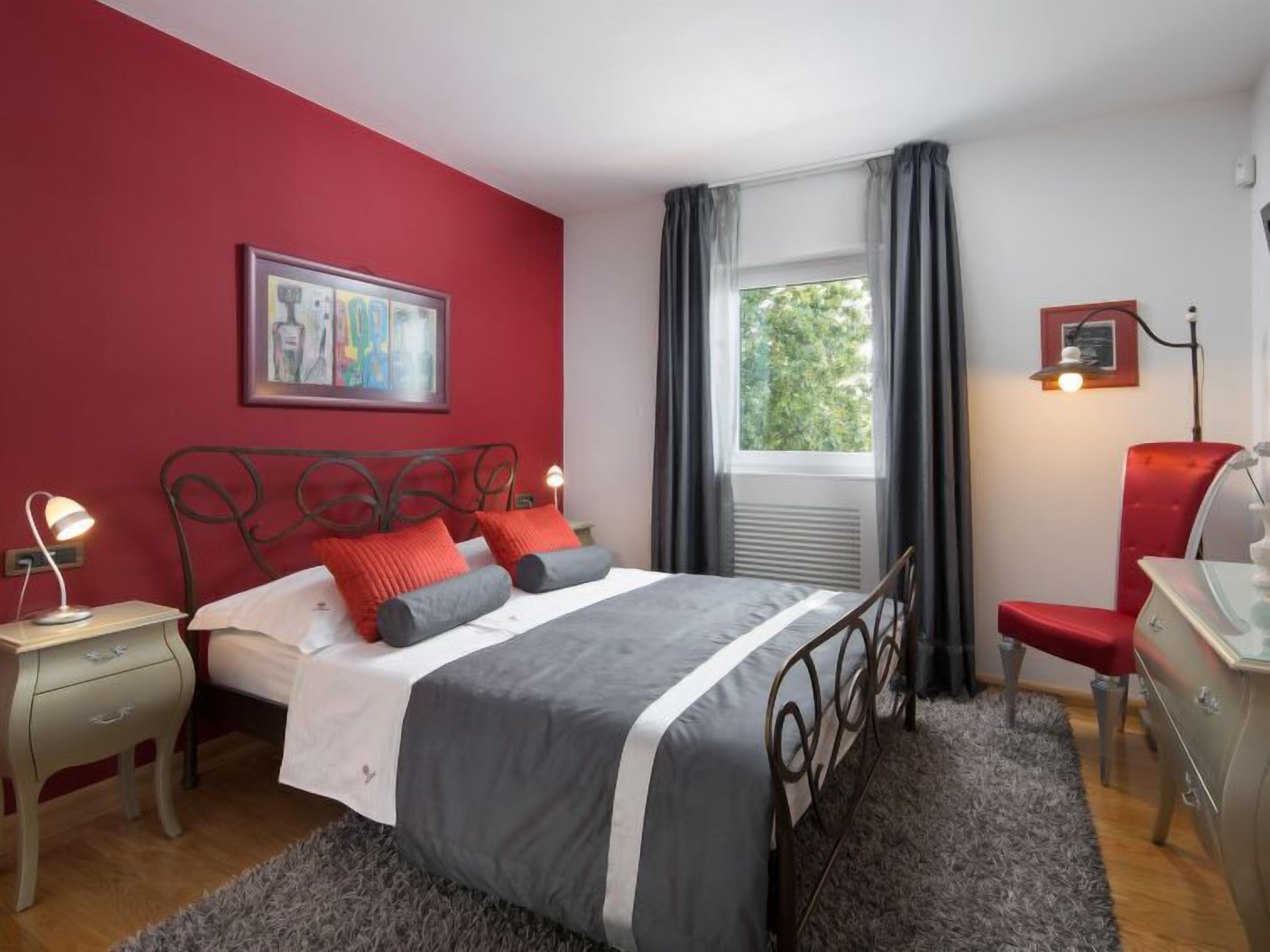 Un dormitorio con cama, mesita de noche, silla, cómoda y ventana con cortinas.