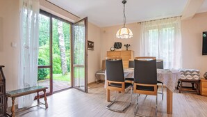 A dining area with a table, chairs, and a bench. There is a sliding glass door leading to a garden. - Borowikowa by Interhome (Sasino)