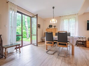 A dining area with a table, chairs, and a bench. There is a sliding glass door leading to a garden.