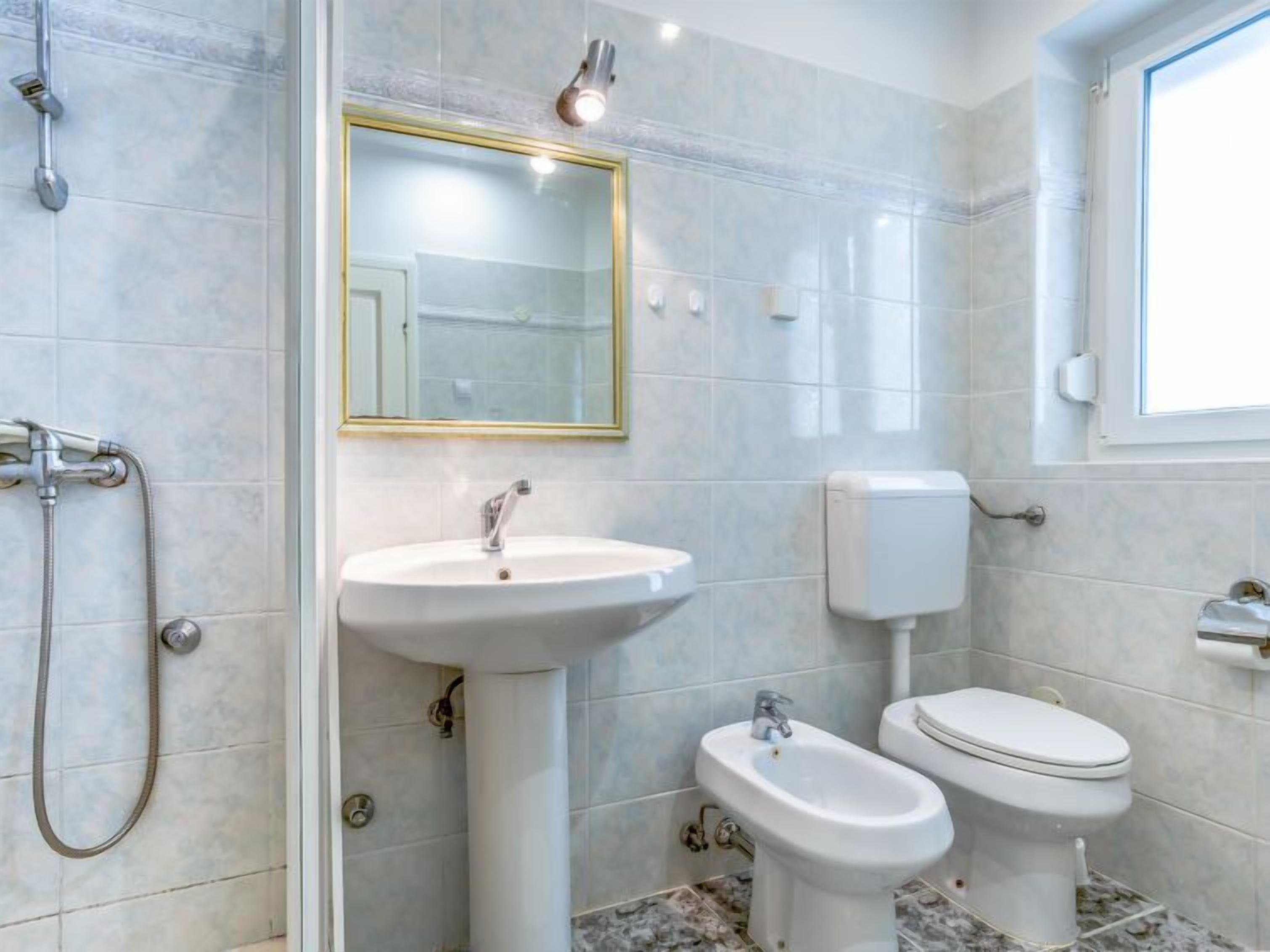Ein Badezimmer mit einem Standwaschbecken, einem Bidet, einer Toilette und einer Dusche inklusive Handbrause.