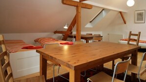 A cozy attic room with a wooden dining table, chairs, and a loft-style bed with striped bedding. - Kleine Winten by Interhome (Geinberg)