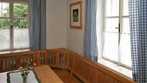 A room with a wooden bench, a table with a vase of flowers, and checkered curtains on the windows. - Kleine Winten by Interhome (Geinberg)