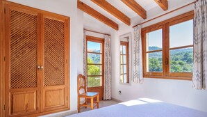 A bedroom with a bed, wooden wardrobe, and two windows with curtains.