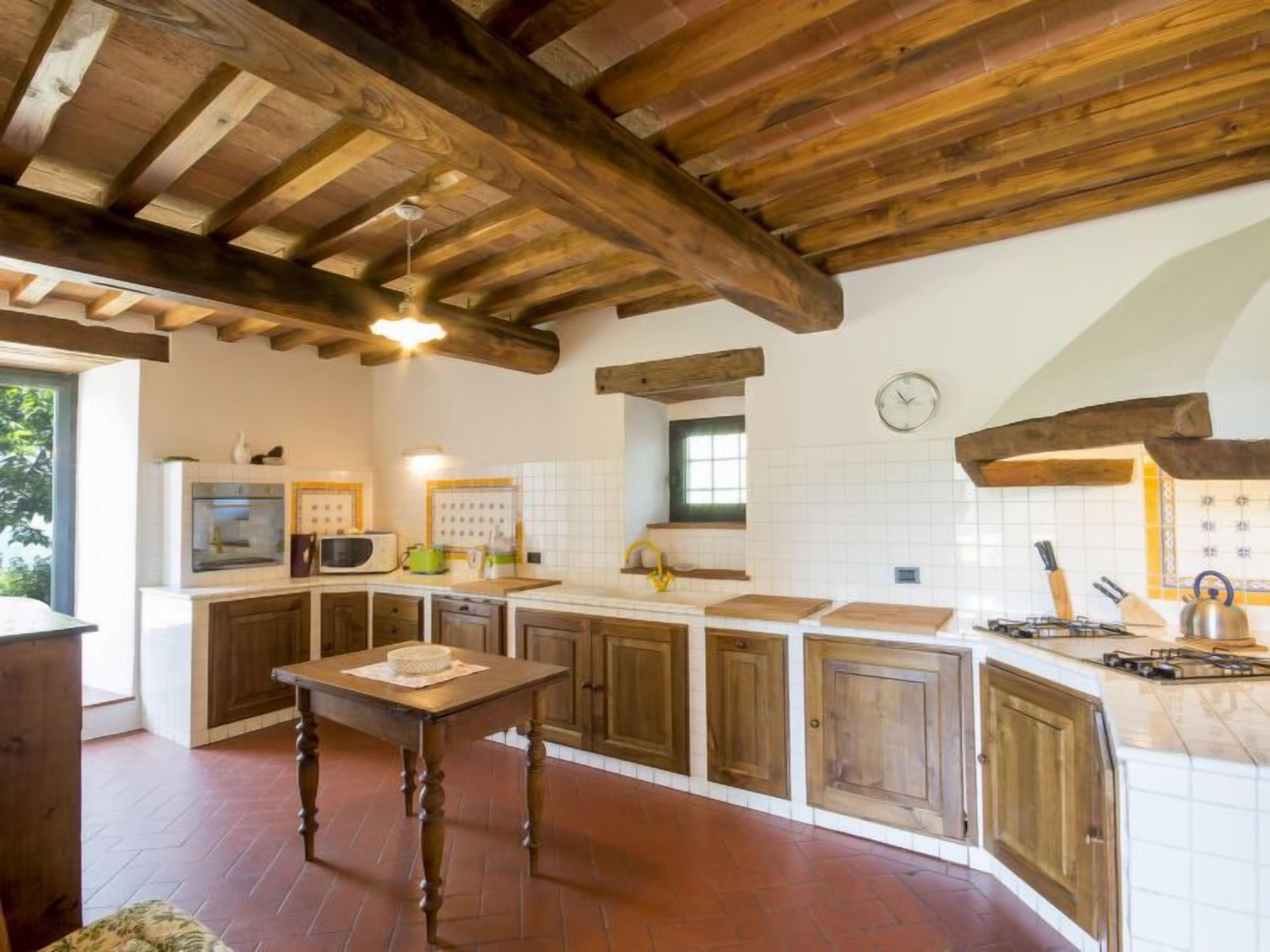 A rustic kitchen with wooden beams, a central island, and a clock on the wall.