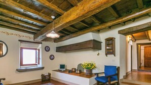 A rustic interior with exposed wooden beams, a glass coffee table, a blue chair, and a wooden bench.