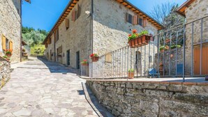 A narrow cobblestone street flanked by stone buildings with wooden shutters and flower boxes.