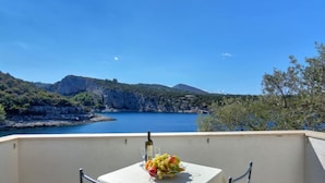 A balcony with a table set for two, overlooking a scenic coastal landscape with cliffs and a body of water. - Apartment Cico by Interhome (Hvar/Pokrivenik)