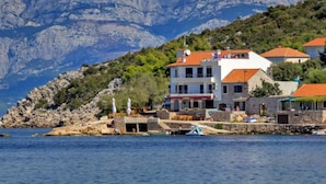 A coastal building with a stone facade, multiple balconies, and a red-tiled roof. - Apartment Cico by Interhome (Hvar/Pokrivenik)