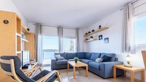 A modern living room with a sofa, a rocking chair, a small table, and a balcony with a view. - Nou Salou by Interhome (Salou)