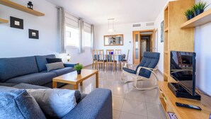 A modern living room with a sofa, coffee table, and TV stand. There is a dining area with chairs and a table. - Nou Salou by Interhome (Salou)
