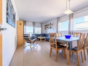Ein modernes Wohnzimmer mit Sofa, Esstisch, Stühlen und Blick zum Himmel.