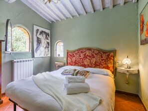 Een slaapkamer met een bed, een radiator, een raam en een lamp.