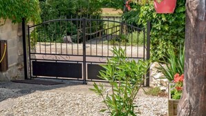 A gated entrance with a gravel driveway leading to a paved path.