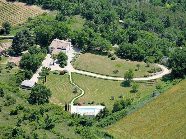 Vista aérea de una propiedad con una casa grande, jardines cuidados y una piscina.