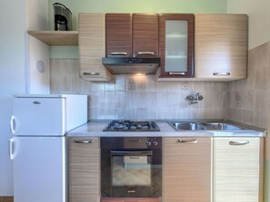 Een koelkast, een oven, een vaatwasser, kookgerei, borden en bestek