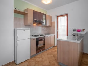 Een koelkast, een oven, een vaatwasser, kookgerei, borden en bestek
