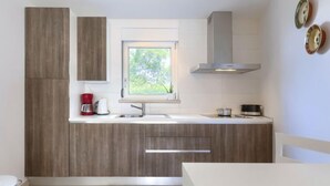 Een moderne keuken met houten kasten, een raam met uitzicht, een inbouwfornuis en een koffiezetapparaat.