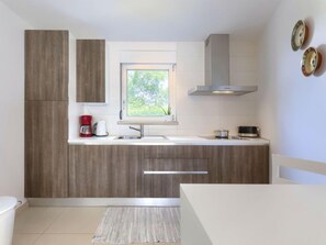 Une cuisine moderne avec des meubles en bois, une fenêtre offrant une belle vue, une cuisinière encastrée et une machine à café.