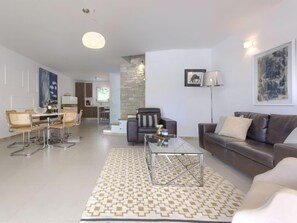 A modern living room with a dining area, a sofa, a coffee table, and a lamp.