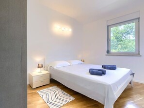 A modern bedroom with a large bed, bedside lamps, a window, and a chevron-patterned rug.