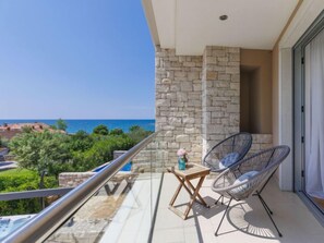 A balcony with stone walls, two wicker chairs, a small wooden table, and a view of the sea. - Sv. Ivan 2 by Interhome (Umag)