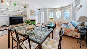 Un amplio salón con televisor, mesa de vidrio, sofás y chimenea.