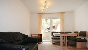 Ein modernes Wohnzimmer mit einer schwarzen Ledersofa, einem Holzespeisetisch mit Bänken und einem großen Fenster mit Vorhängen.