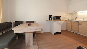 Eine kompakte Küche mit Holztisch, Mikrowelle und Kaffeemaschine.