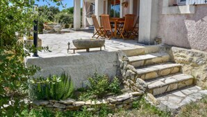 Une maison en pierre dotée d’un patio, d’un espace salon extérieur et d’un escalier en pierre menant à l’entrée.